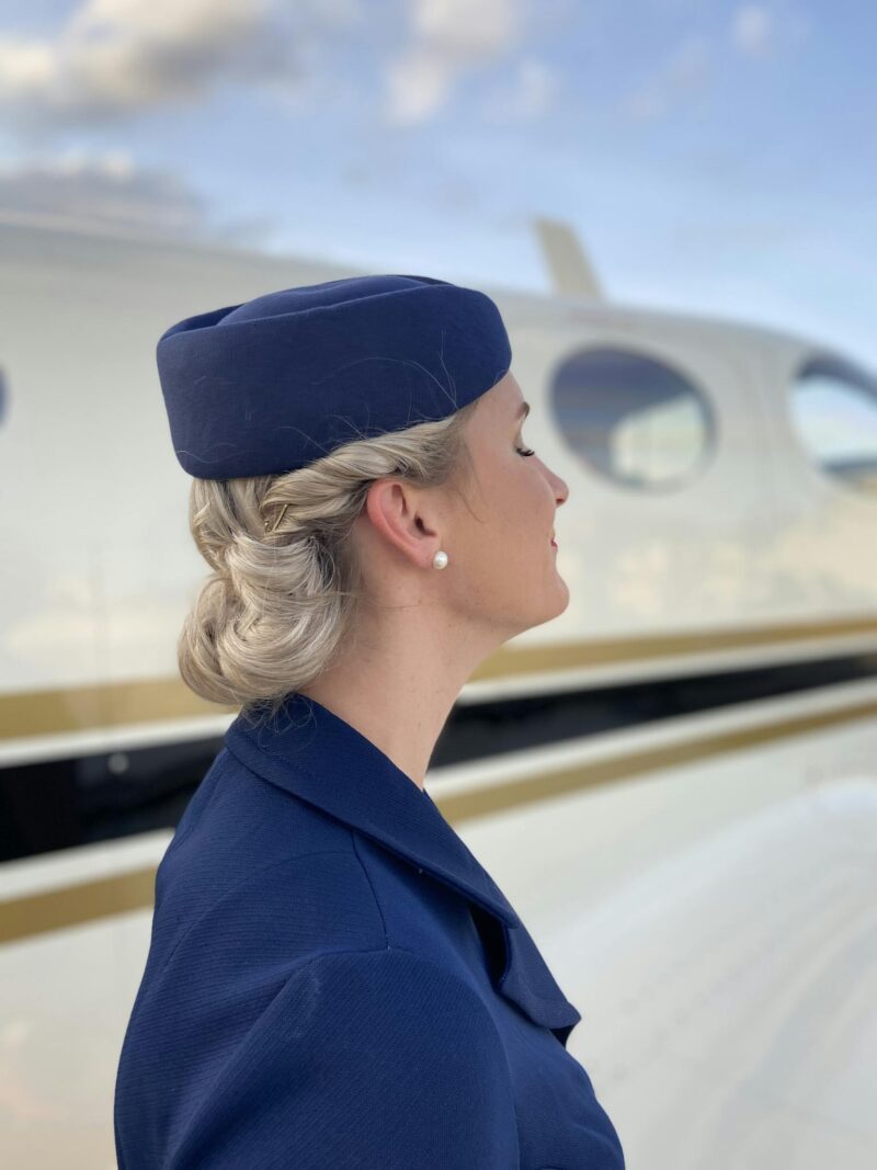 Side view of flight attendant in uniform standing outside an airplane.