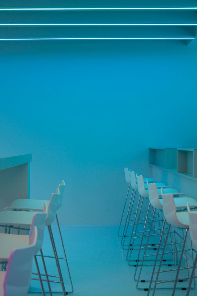 Sleek minimalist interior with white chairs and blue neon lighting, creating a modern and futuristic ambiance.