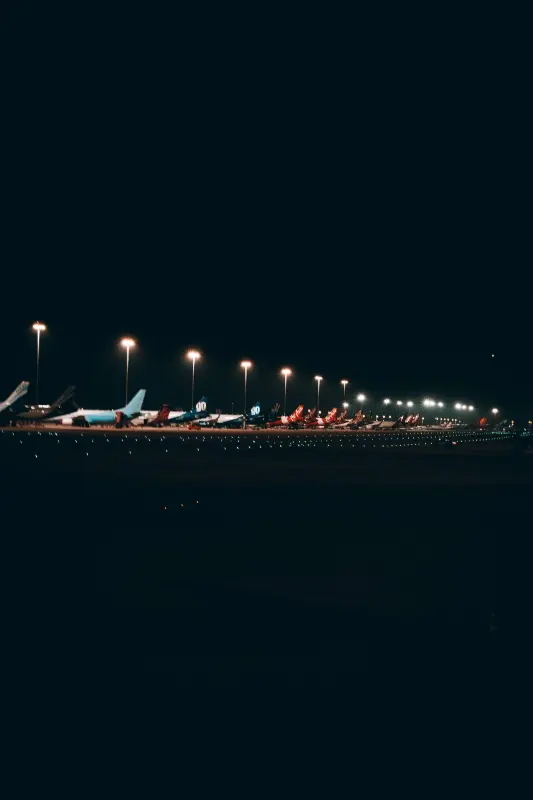 Night view of airplanes and runway lights at Belgrade Nikola Tesla Airport.