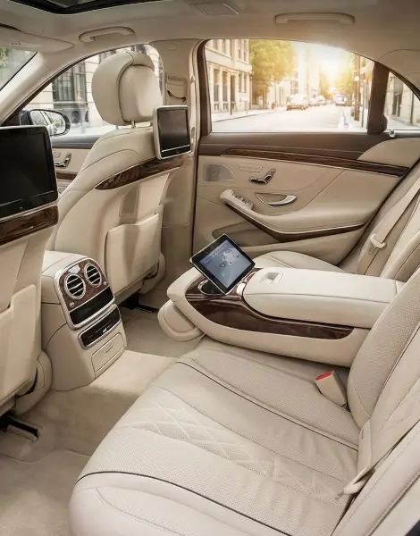 Spacious interior of a luxury sedan featuring beige leather seats, legroom, and rear entertainment screens.
