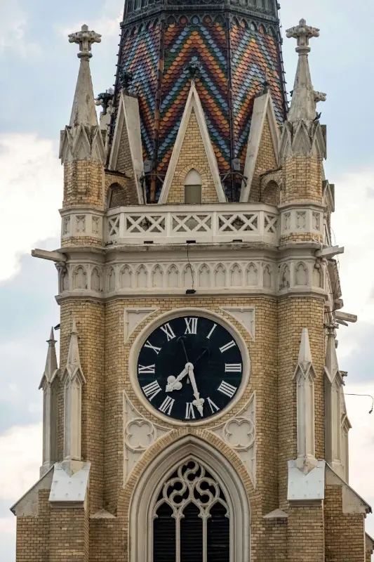 Detailed view of the colorful tiled roof and clock tower of the Name of Mary Church in Novi Sad.